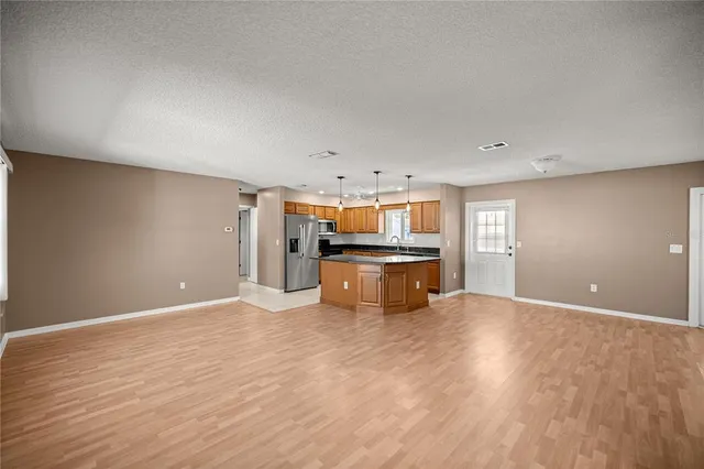 a view of an empty room with window and wooden floor