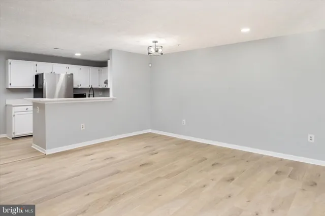 a view of kitchen and empty room with wooden floor