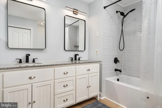 a bathroom with a granite countertop sink mirror and a bathtub