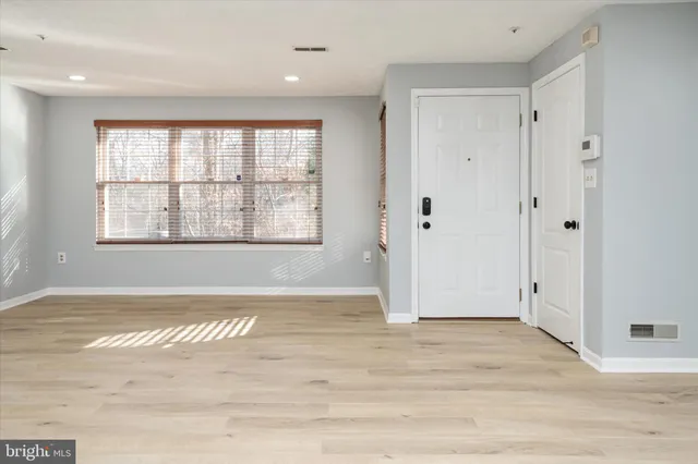 an empty room with wooden floor and windows