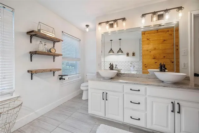 a bathroom with a granite countertop sink a toilet and shower