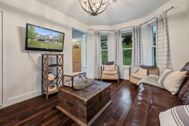 a living room with furniture a floor to ceiling window and wooden floor