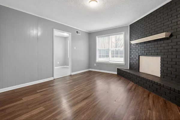 a view of empty room with wooden floor and fireplace