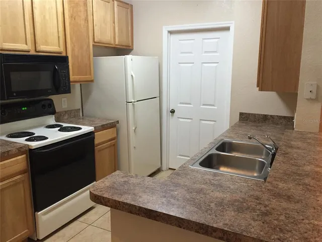 a kitchen with granite countertop a refrigerator stove and sink