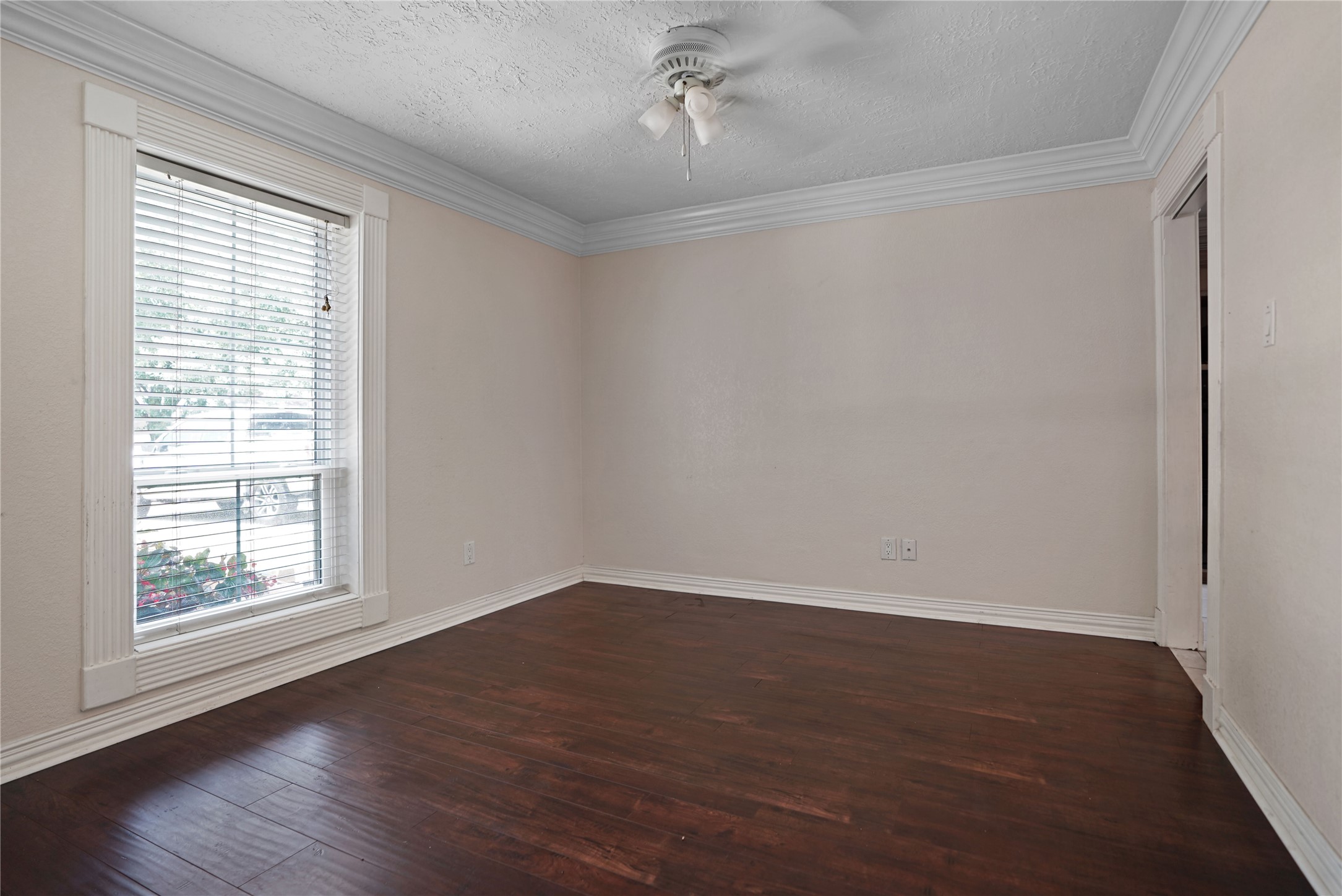 17119 Mellow Ridge Drive Spring, TX 77379 - Photo 16 of 32 This room features dark hardwood floors, a large window with blinds providing natural light, neutral walls, and a ceiling fan, offering a cozy and versatile space.