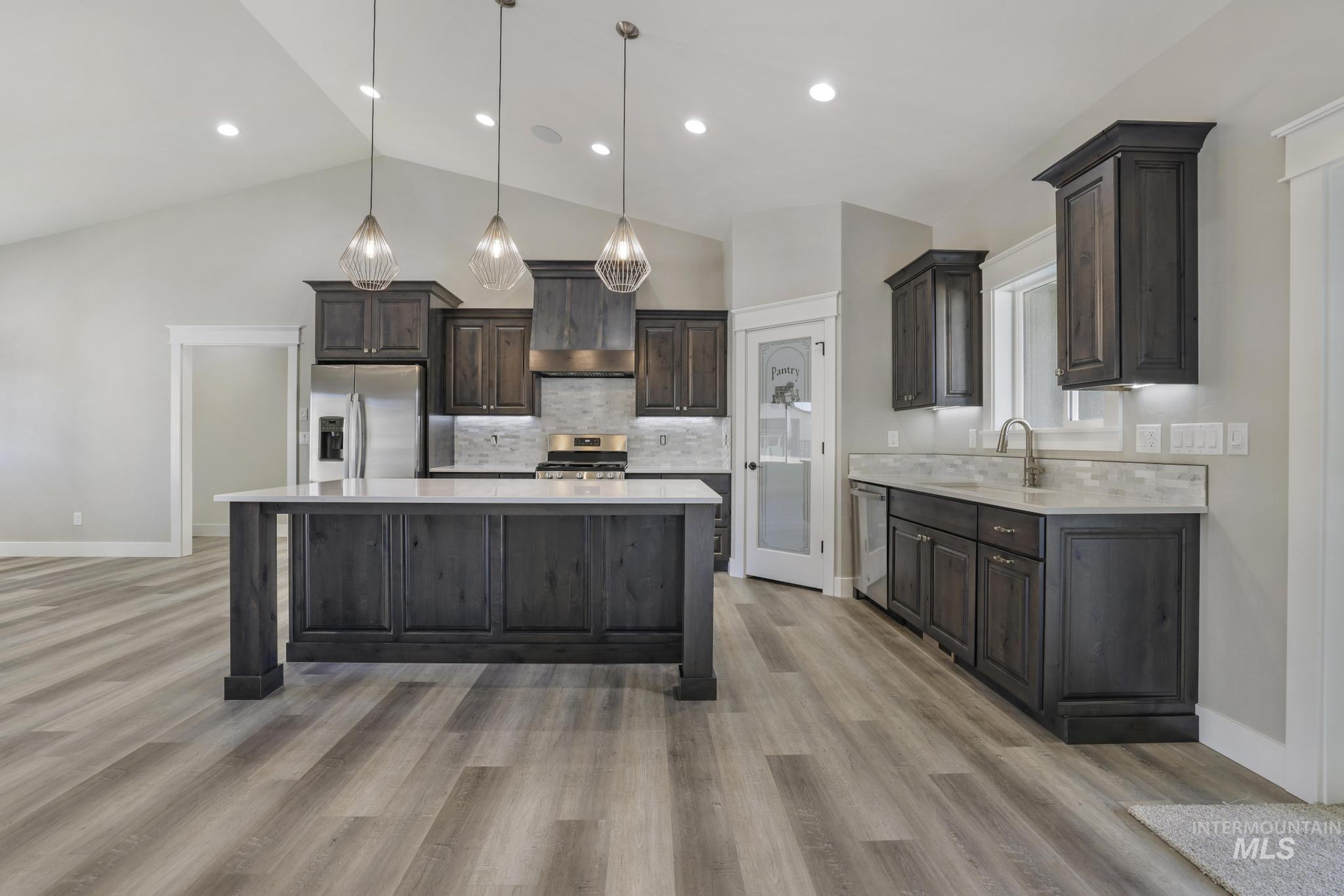 298 Sandi Road Twin Falls, ID 83301 - Photo 2 of 24 Spacious kitchen featuring dark wood cabinetry, a large center island with a light-toned countertop, and a matching backsplash