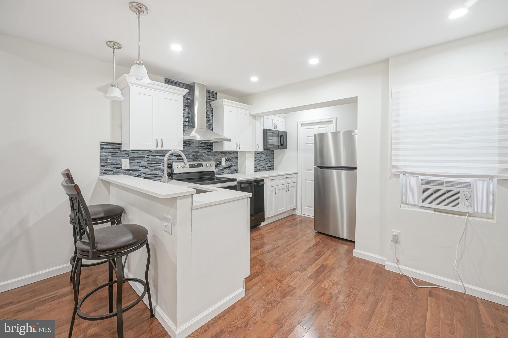 1929 North 9th Street Philadelphia, PA 19122 - Photo 2 of 49 a kitchen with kitchen island white cabinets and stainless steel appliances