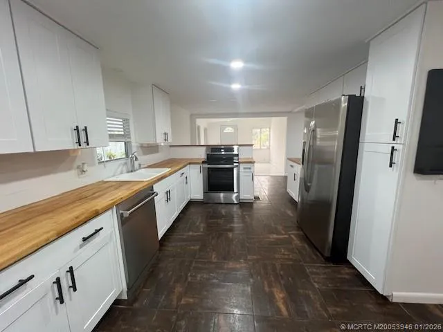 a large kitchen with a refrigerator a sink a stove top oven and cabinets