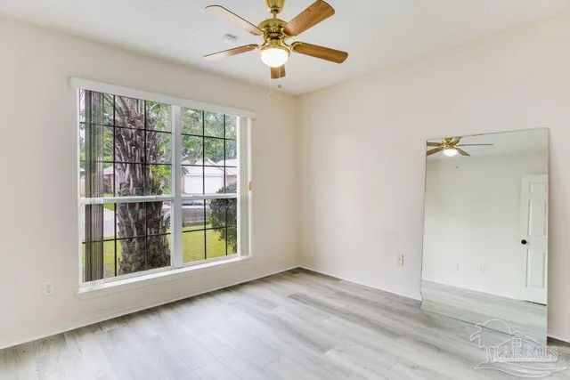 a view of an empty room and chandelier fan