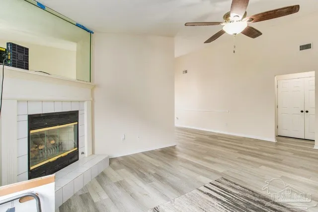 an empty room with wooden floor and ceiling fan