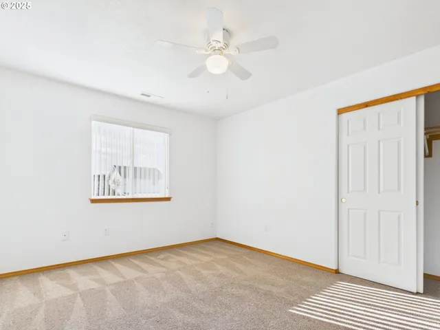 an empty room with a window and a ceiling fan
