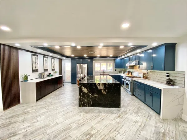 a large white kitchen with a large counter top and stainless steel appliances