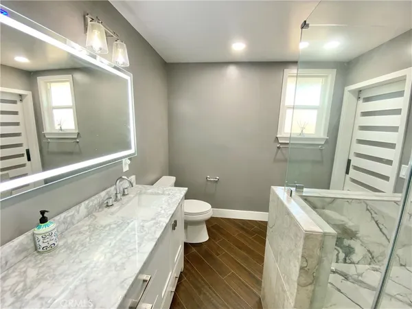 a bathroom with a granite countertop sink a toilet and a mirror