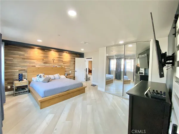 a spacious bedroom with a bed and wooden floor
