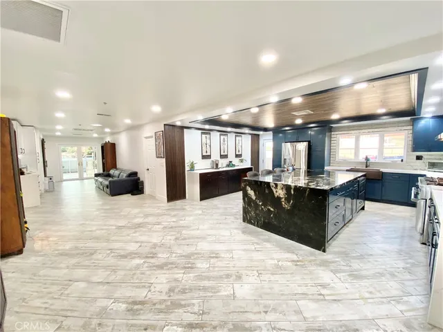 a large kitchen with stainless steel appliances kitchen island a large counter top a refrigerator and a sink