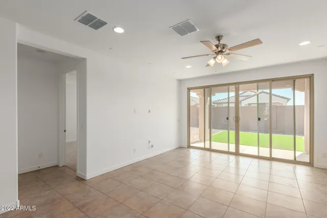 a view of an empty room with kitchen and window
