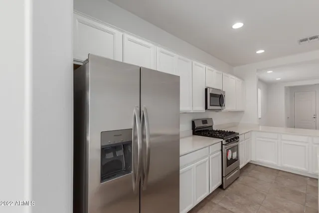 a kitchen with stainless steel appliances a stove a sink a microwave a refrigerator and cabinets