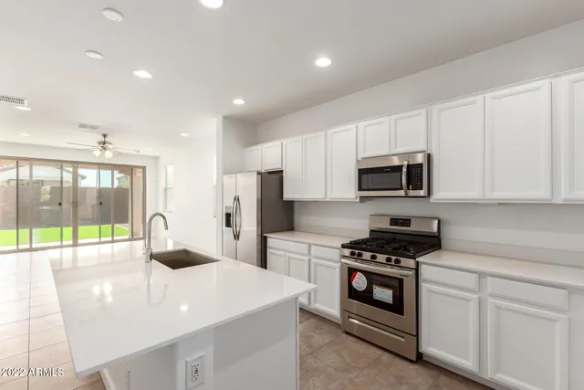 a large white kitchen with sink and microwave
