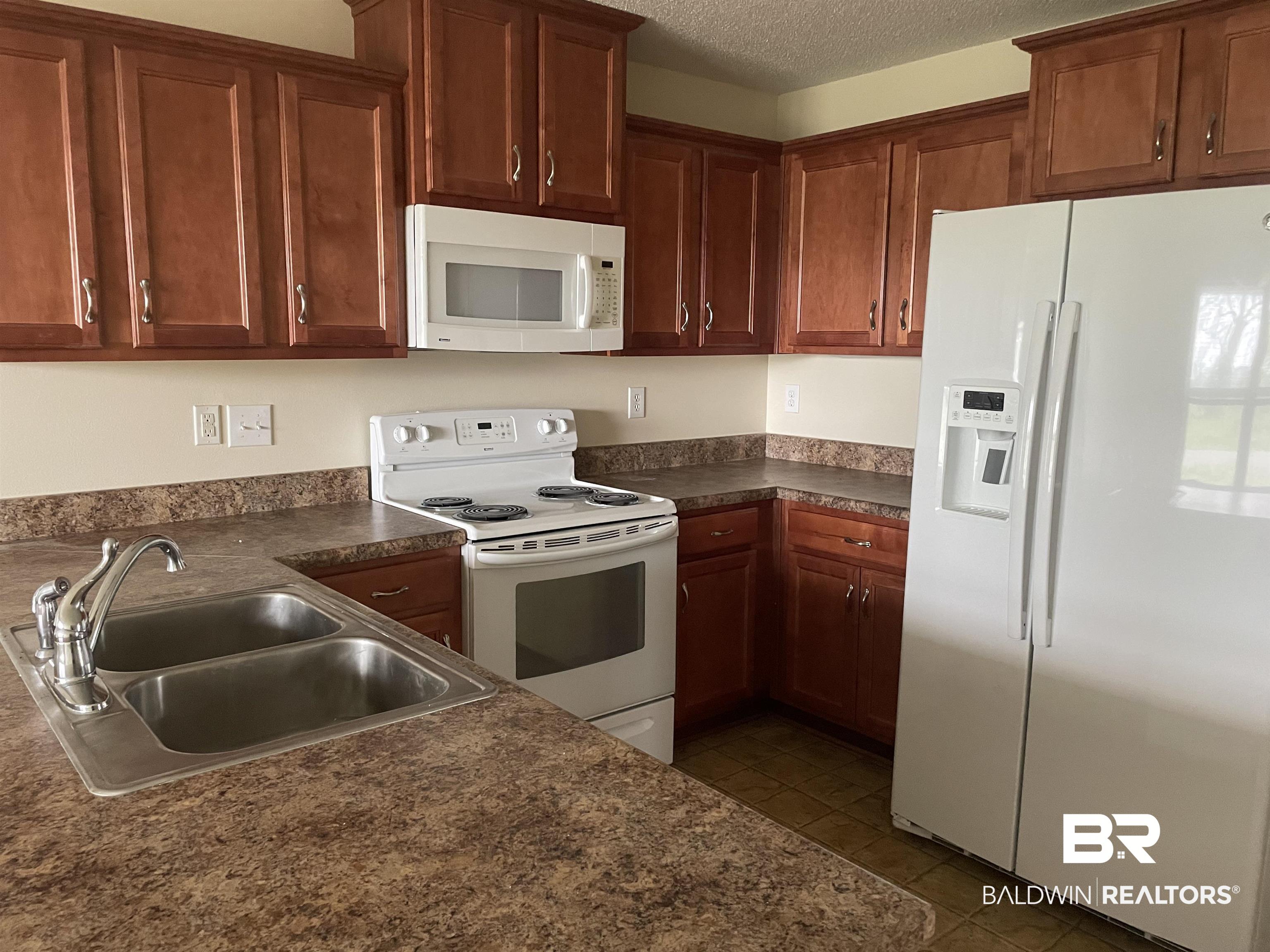 23575 Fountain Street Robertsdale, AL 36567 - Photo 11 of 19 Kitchen featuring dark countertops, white appliances, a textured ceiling, and a sink