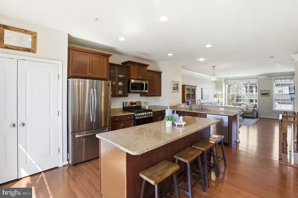 a kitchen with stainless steel appliances granite countertop a refrigerator a stove a sink a dining table and chairs with wooden floor