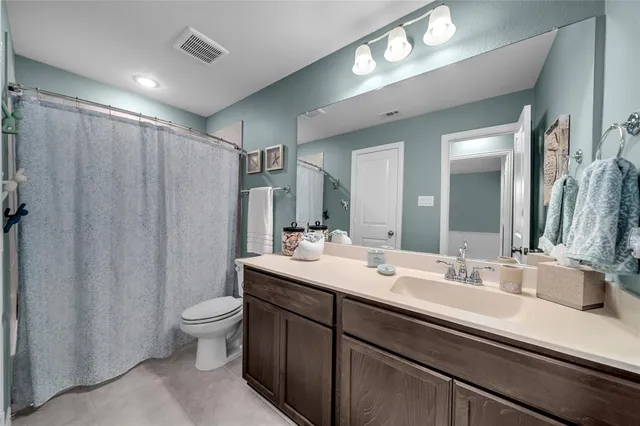 a bathroom with double vanity sink a toilet and a large mirror