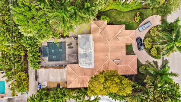 an aerial view of a house with outdoor space and trees all around