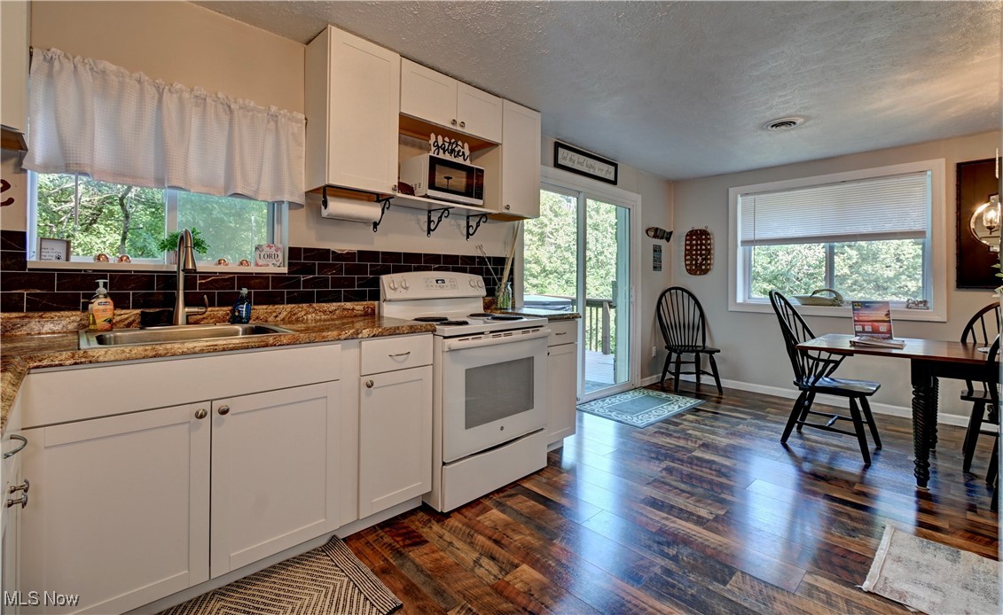 2227 Elk Road Southwest Carrollton, OH 44615 - Photo 28 of 40 Kitchen with white appliances, white cabinets, plenty of natural light, dark wood-type flooring, and a textured ceiling
