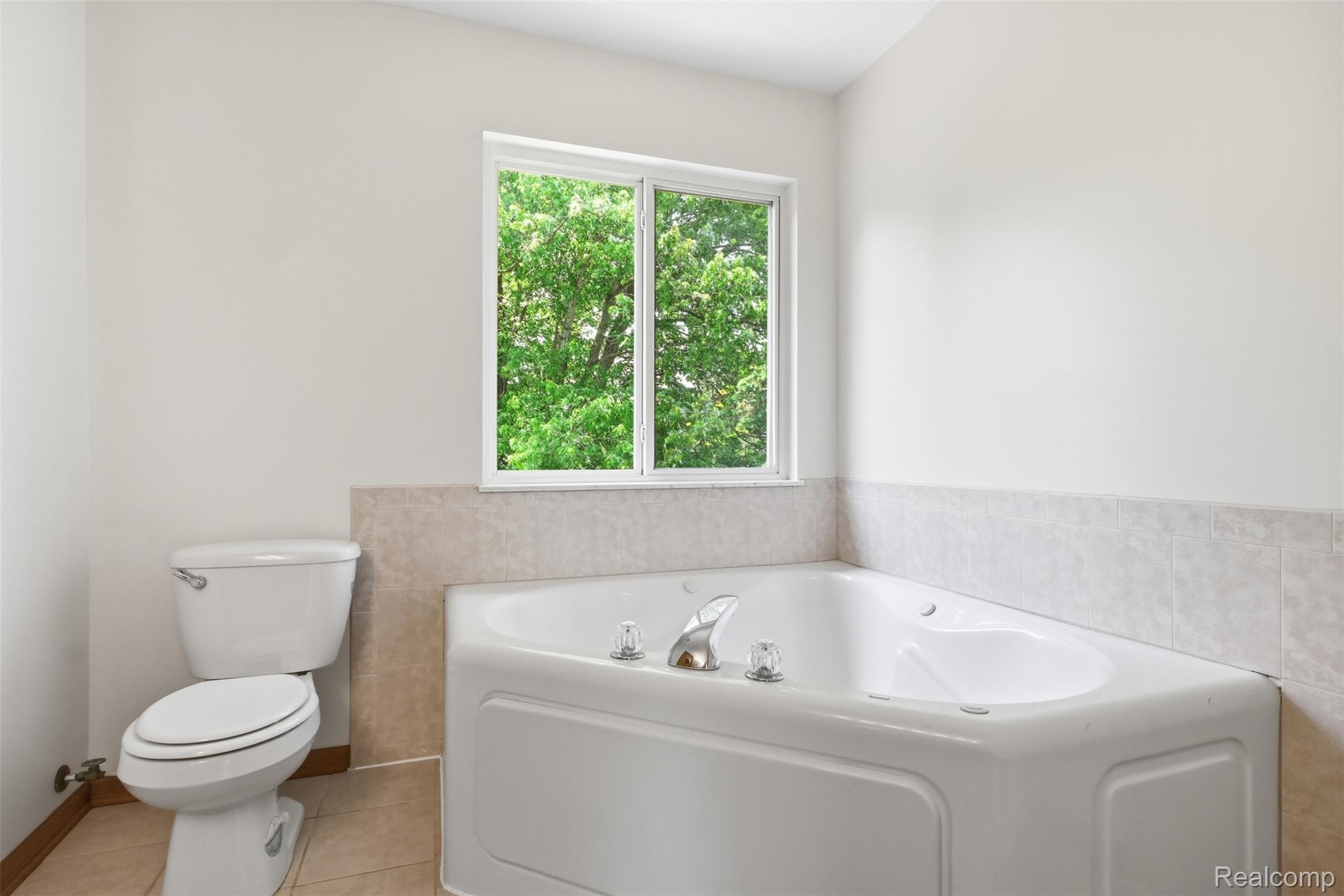4482 Pleasant Valley Road Brighton, MI 48114 - Photo 20 of 35 Bathroom featuring a corner soaking tub, tile flooring, and a window providing natural light