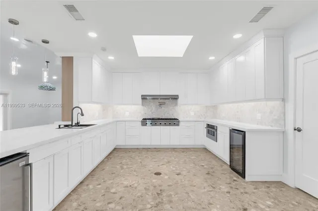 a kitchen with stainless steel appliances a stove and white cabinets