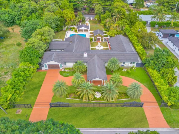 an aerial view of residential houses with outdoor space and trees all around