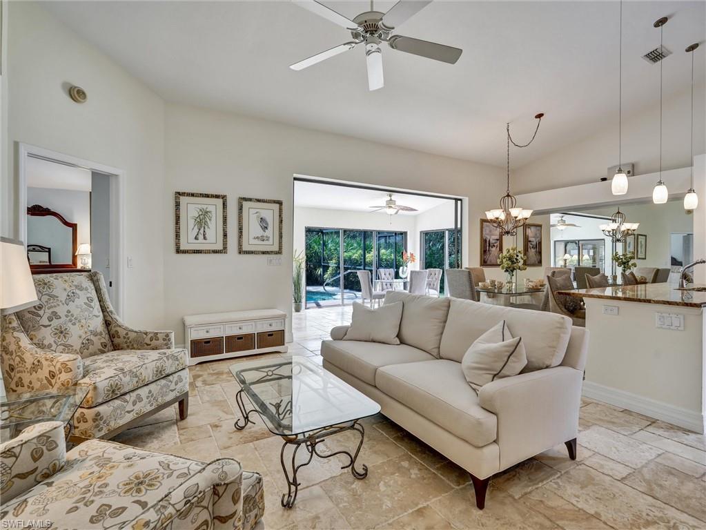 241 St James Way Naples, FL 34104 - Photo 5 of 34 Living room featuring lofted ceiling, a ceiling fan, stone tile floors, and a chandelier