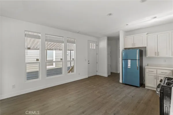 a view of empty room with a kitchen and refrigerator