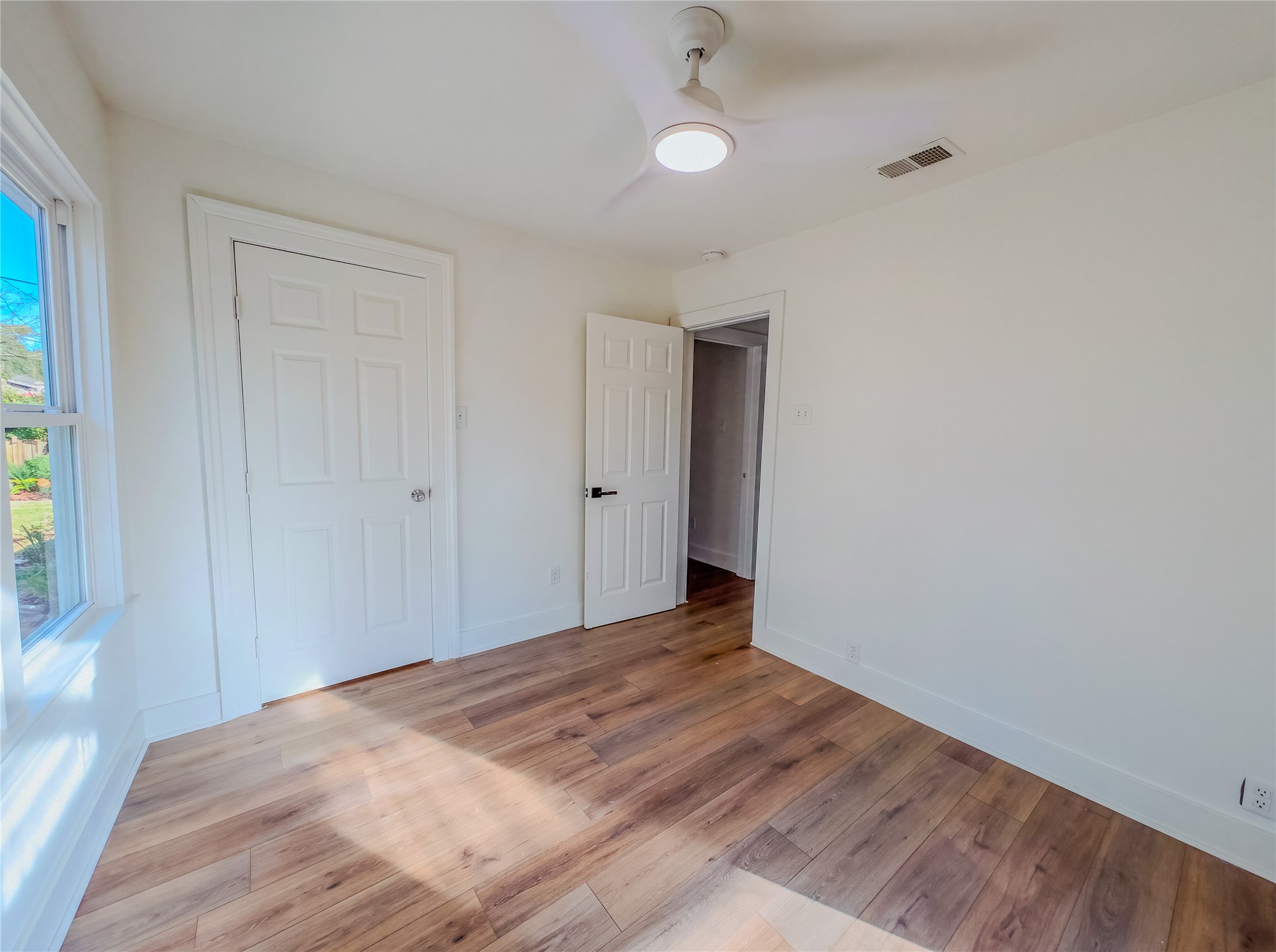 1120 Mark Street Austin, TX 78721 - Photo 13 of 22 Rich wood-patterned flooring and crisp white trim enhance this inviting bedroom space.