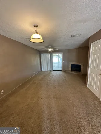 an empty room with a chandelier fan and windows
