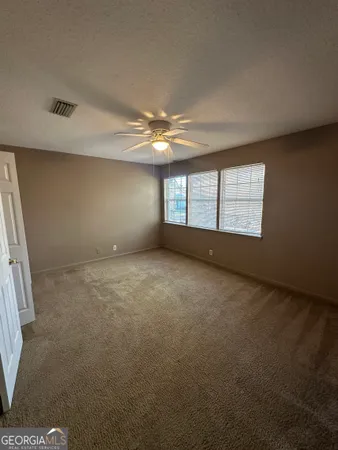 a view of an empty room with chandelier fan and window