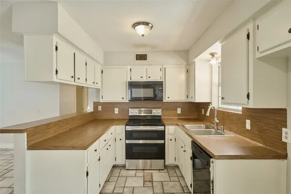 a kitchen with granite countertop a sink stove and cabinets
