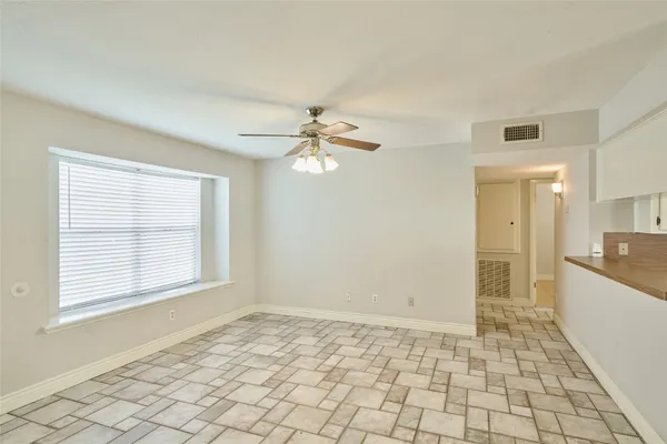 a view of an empty room with window and chandelier fan