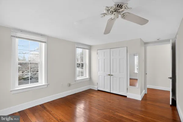 an empty room with wooden floor closet and windows