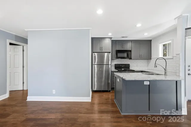 a kitchen with stainless steel appliances granite countertop a refrigerator a sink and a stove