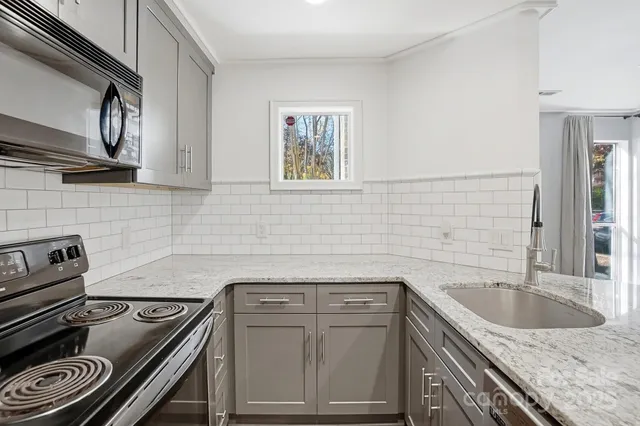 a kitchen with granite countertop a sink stove and cabinets