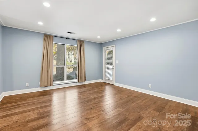 a view of an empty room with wooden floor and a window