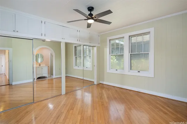 a view of empty room with wooden floor and fan