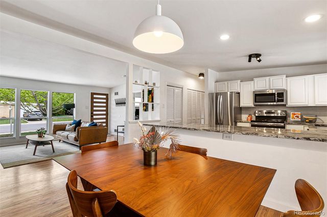 a living room with stainless steel appliances dining table furniture and a wooden floor