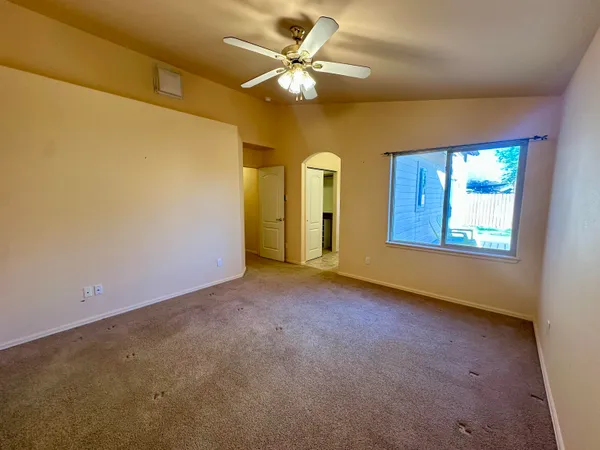 an empty room with windows and fan