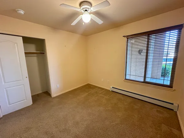 an empty room with closet and a ceiling fan