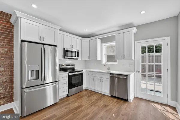 a kitchen with stainless steel appliances granite countertop a refrigerator stove and white cabinets