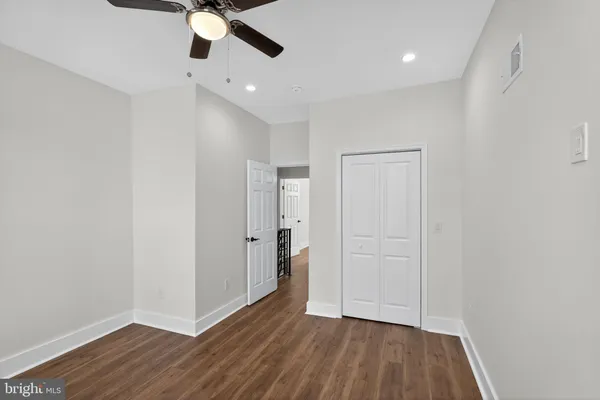 an empty room with wooden floor ceiling fan and windows