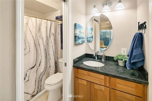 a bathroom with a granite countertop sink a toilet and a mirror
