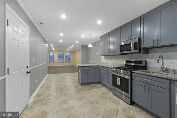 a large kitchen with stainless steel appliances granite countertop a sink a stove and a refrigerator
