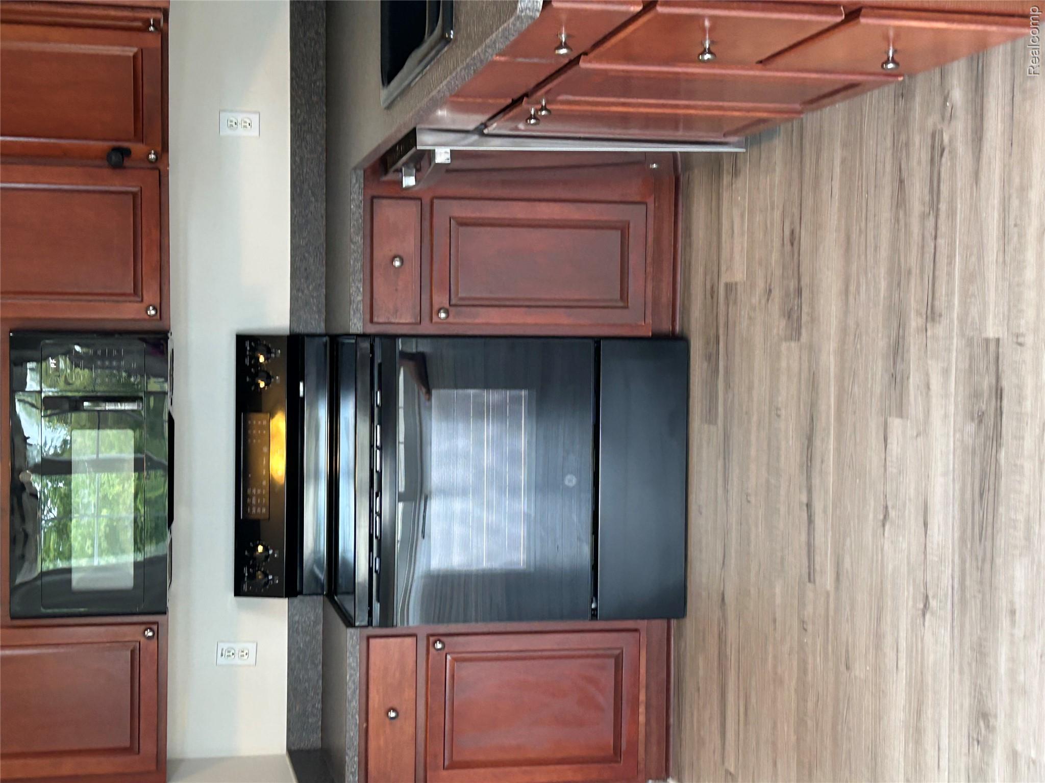 4256 Hampton Ridge Boulevard Howell, MI 48843 - Photo 11 of 25 Kitchen featuring wood-finish cabinetry, dark countertops, a black electric range, and an over-the-range microwave